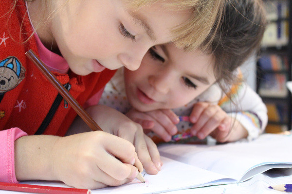 Zwei Kinder schreiben in der Schule in ein Heft
